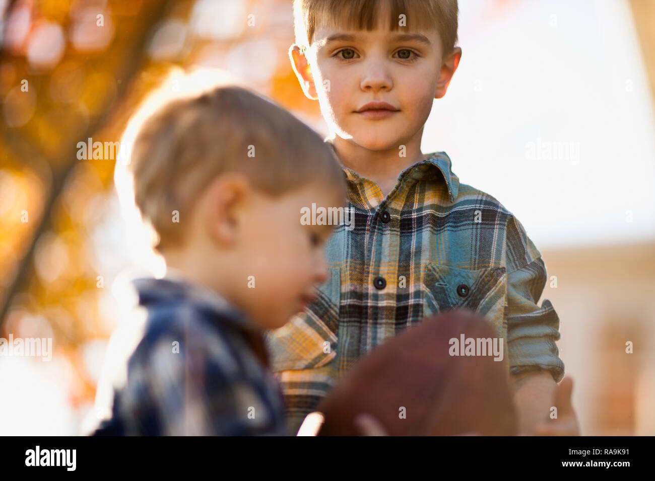 Portrait of boy standing next to his little brother with the rugby ball