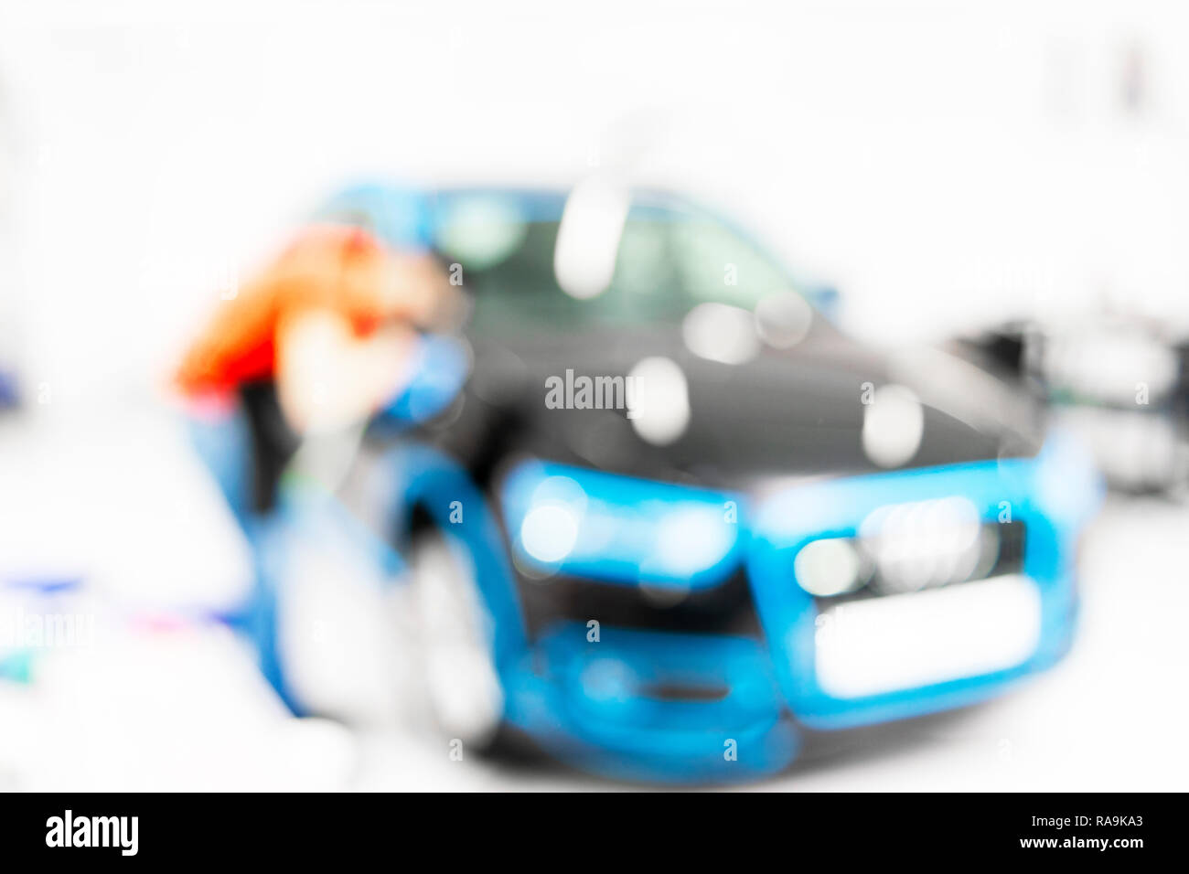 Blurred abstract image of man worker with car in body shop. Blur car auto service. Car bokeh. Blurred background with car in garage. Vehicle maintenan Stock Photo