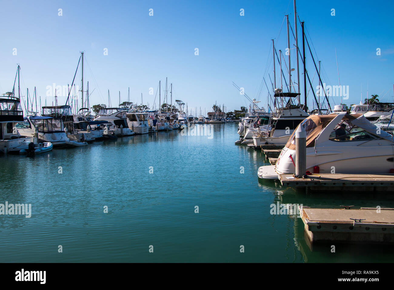 Small marina with deep blue water and many sail and power boats docked in slips Stock Photo