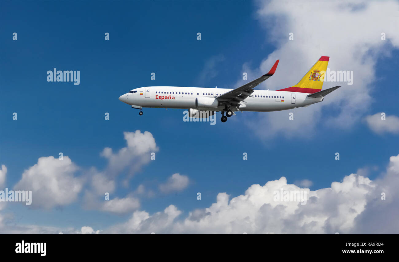 Passenger airplane landing at the airport with flag of Spain on tail. Commercial Spanish jet aircraft with blue cloudy sky in the background Stock Photo