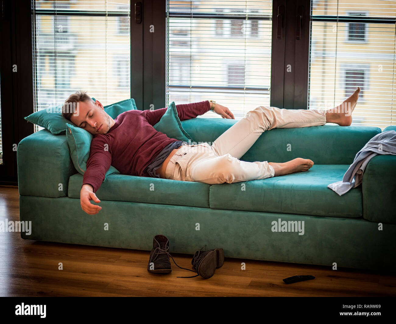 Drunk Man Resting on Couch with head on the Floor Stock Photo