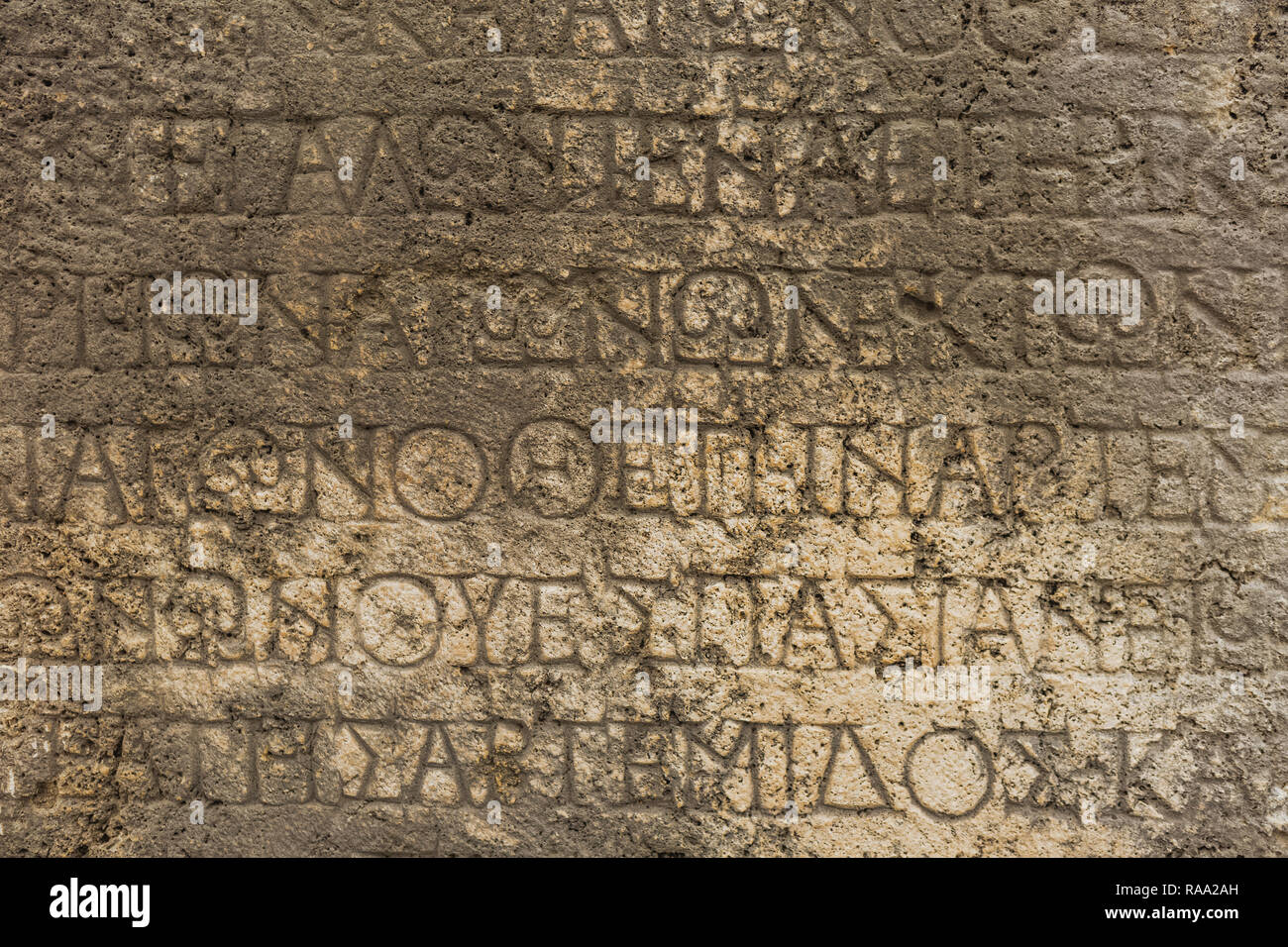 Real ancient letters cutted in stony wall of ancient architecture found during excavations of ancient ruin. Horizontal color photography Stock Photo