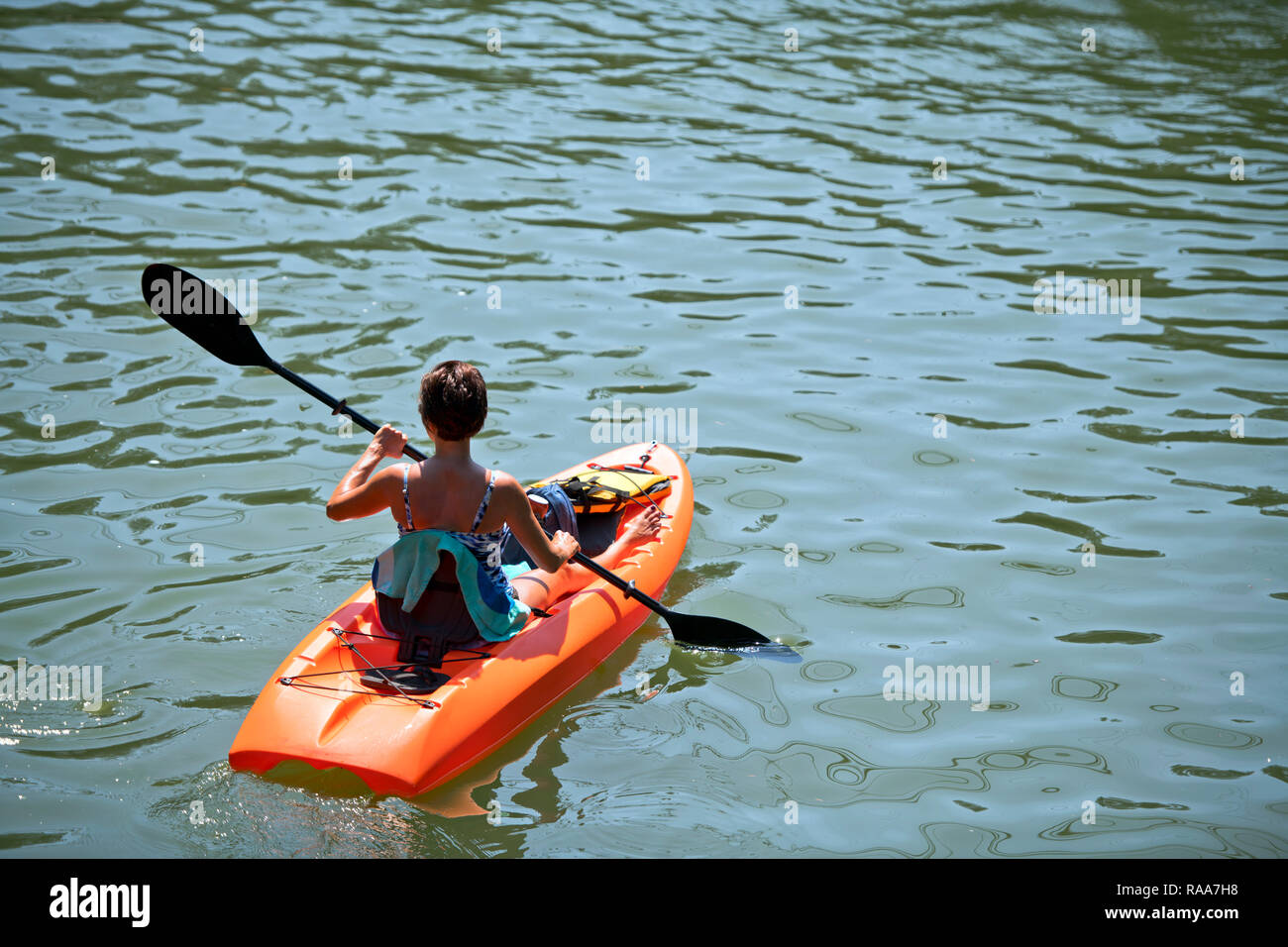 An enthusiast woman with shortcut hair in bathing suit are kayaking on the Lacamas Lake in the