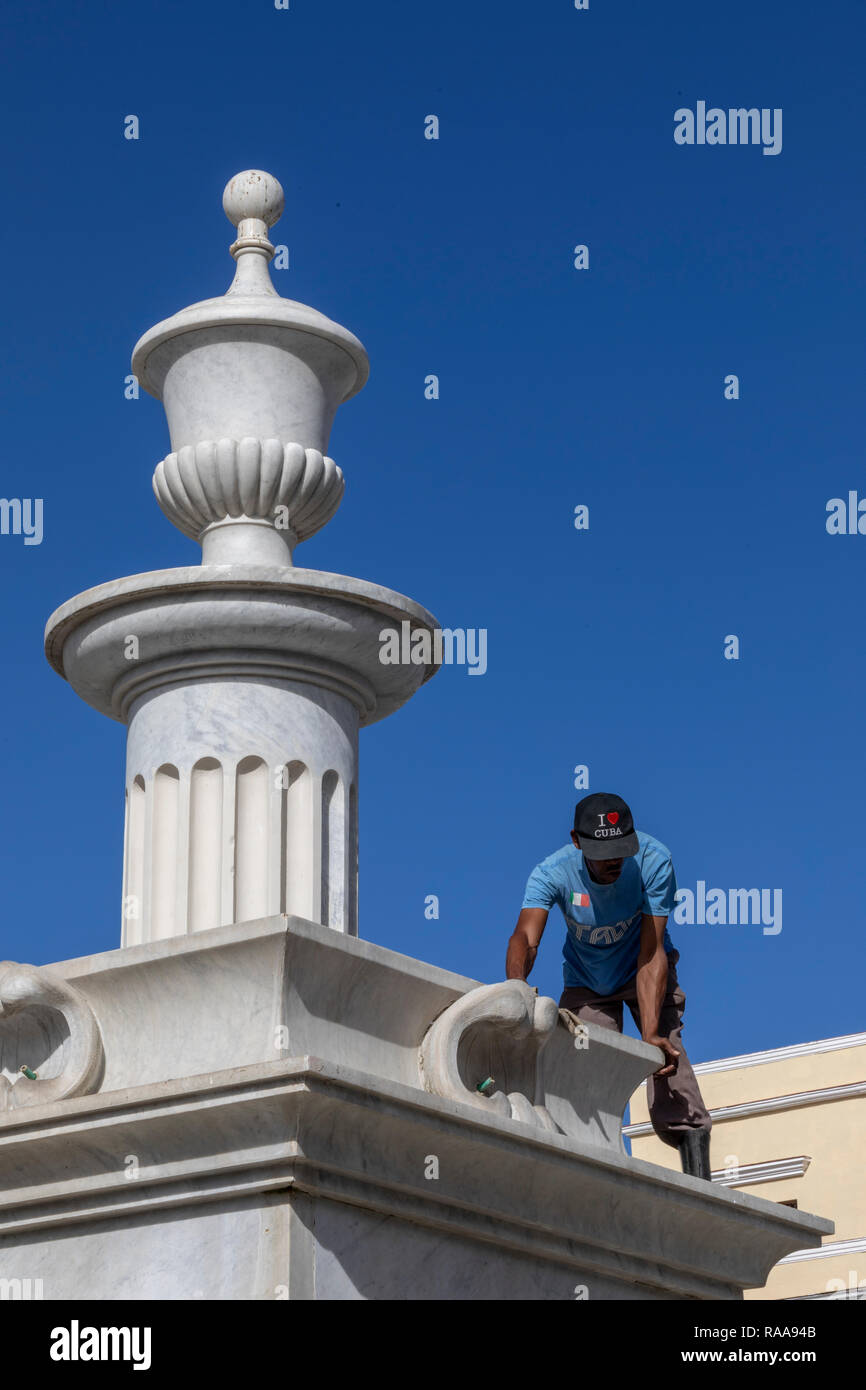 Man wearing Cuba ball cap scrubs fountain in Plaza Vieja, Havana Stock Photo
