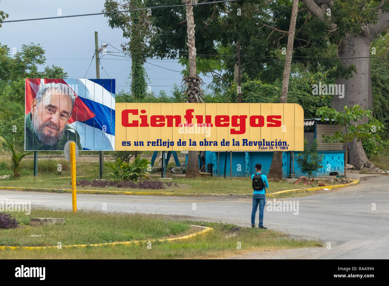 man waits for bus under Fidel Castro propaganda billboard Stock Photo
