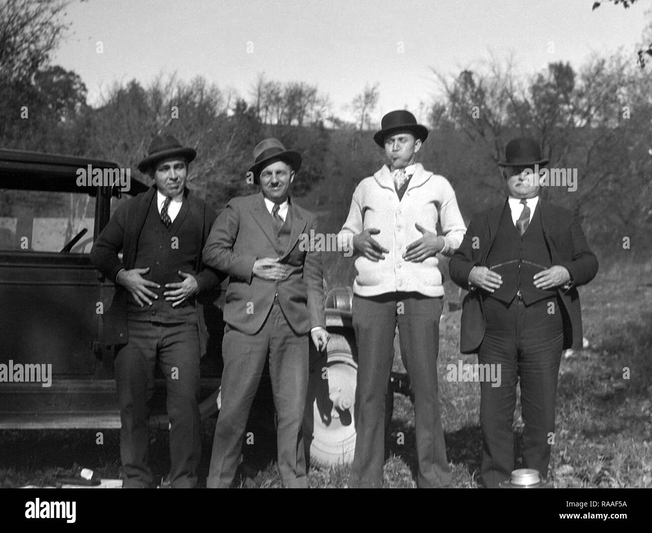 Four well-dressed men seemingly have acquired indigestion all at the same time, ca. 1925. Stock Photo