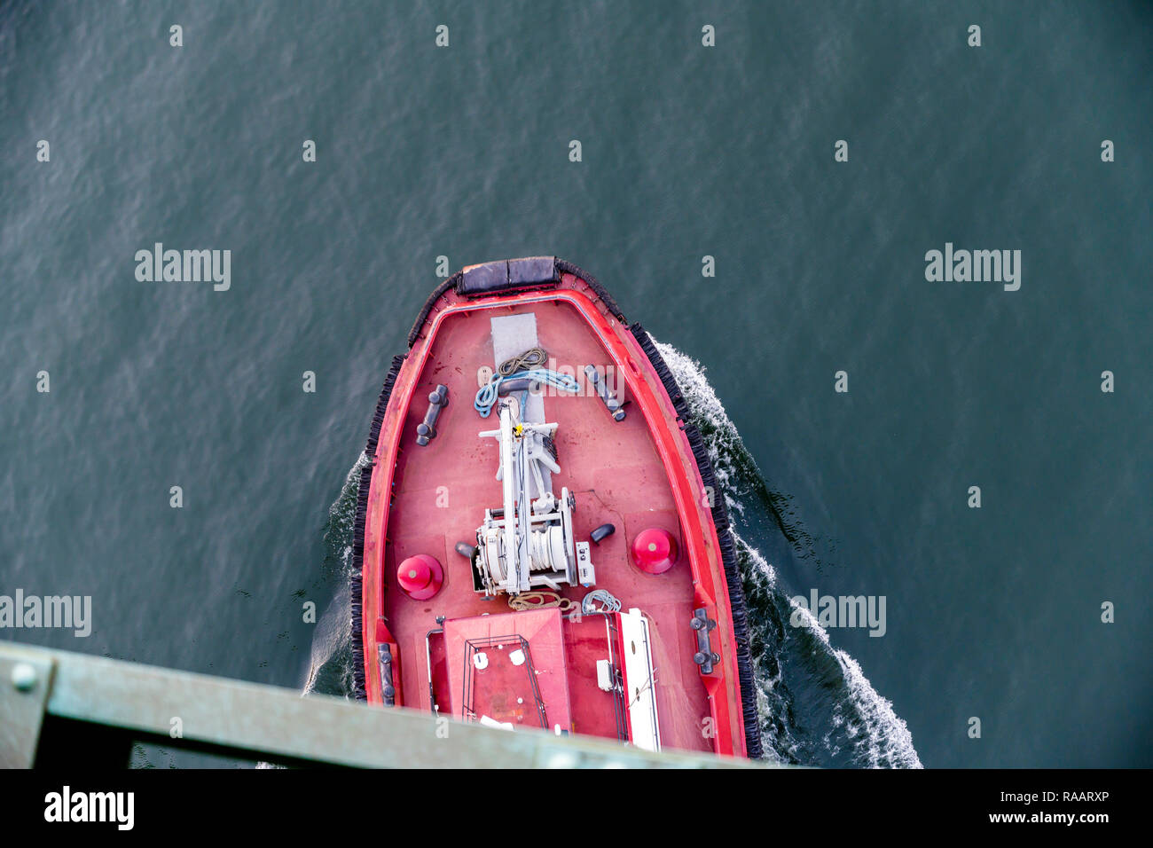 The small red workhorse tugboat surrounded with rubber tires and ...