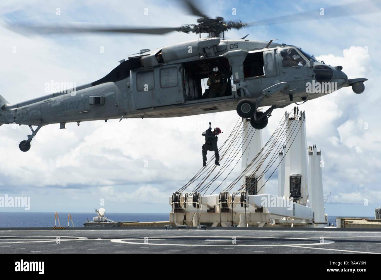 PACIFIC OCEAN (August 23, 2018) - Naval Air Crewman (Helicopter) 2nd Class Jacob Ward, acting crew chief and rescue swimmer assigned to Helicopter Sea Combat Squadron 25 (HSC-25), lowers Hospital Corpsman 2nd Class Kyle Bowen, a search and rescue medical technician assigned to HSC-25, onto the flight deck of the Watson-class vehicle cargo ship USNS Dahl (T-AKR-312) from HSC-25 MH-60S Seahawk helicopter during a medical evacuation drill, August 23. HSC 25 is the Navy’s only forward deployed MH-60S expeditionary squadron. As a part of Helicopter Sea Combat Wing Pacific, it provides an armed heli Stock Photo