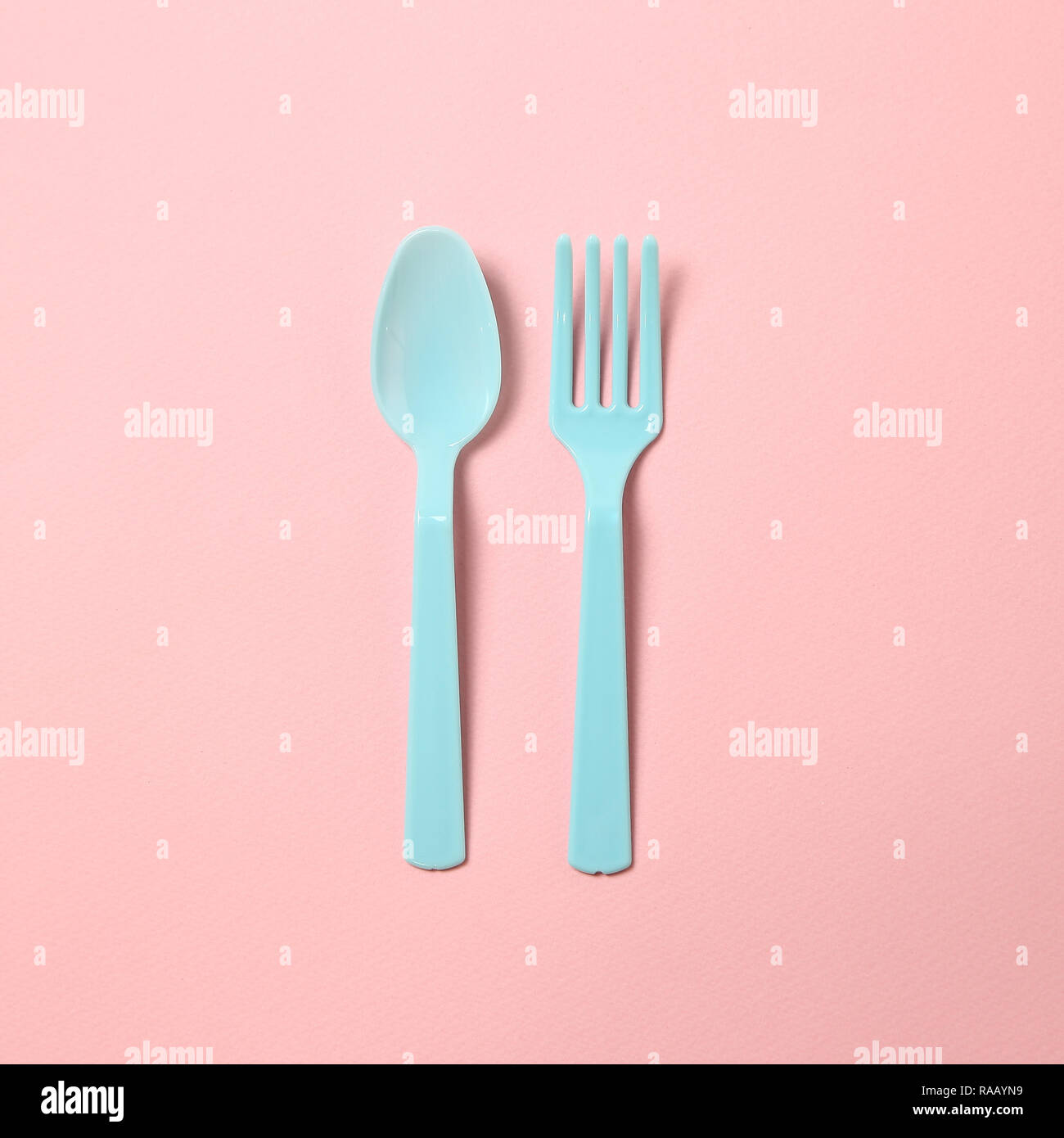 Blue plastic fork and spoon isolated on pink background Stock Photo