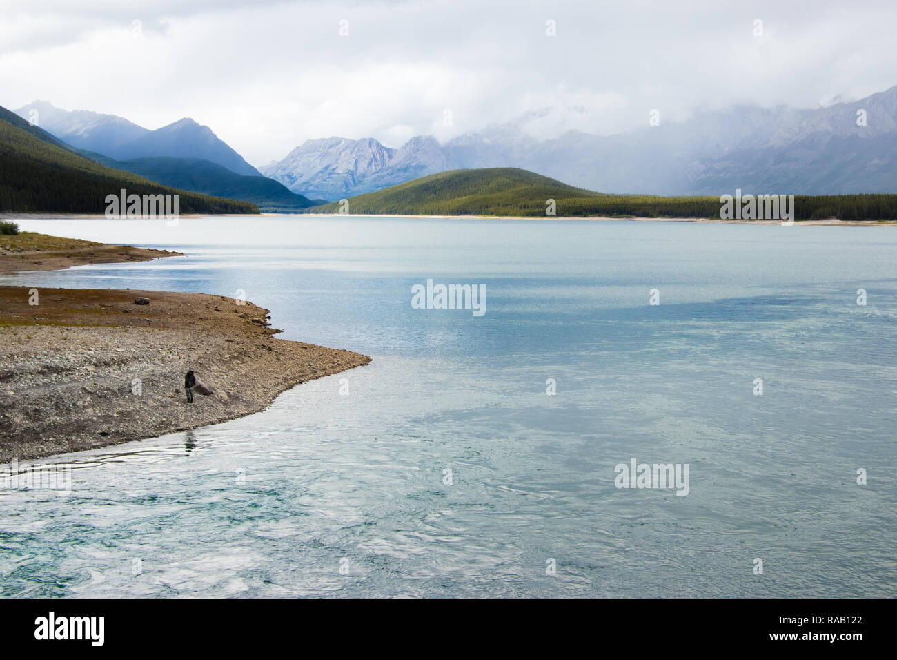 Kananaskis Lower Lake - Rocky Mountains in Summer in a cloudy day and fisherman on the lakeshore - Alberta, Canada Stock Photo