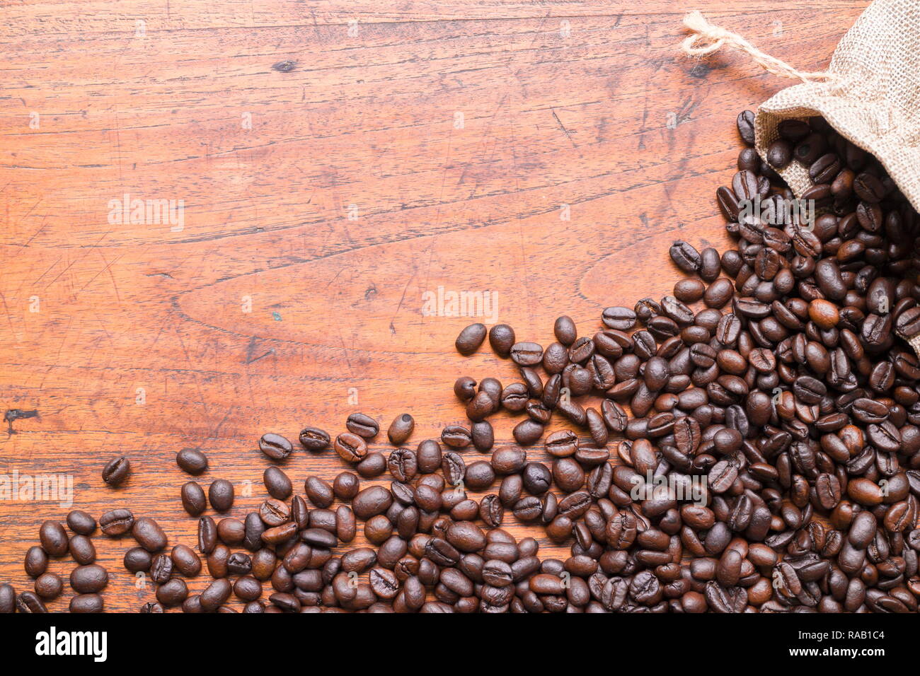 Coffee beans in sack and coffee beans on wooden table with copy space for text or image. Stock Photo