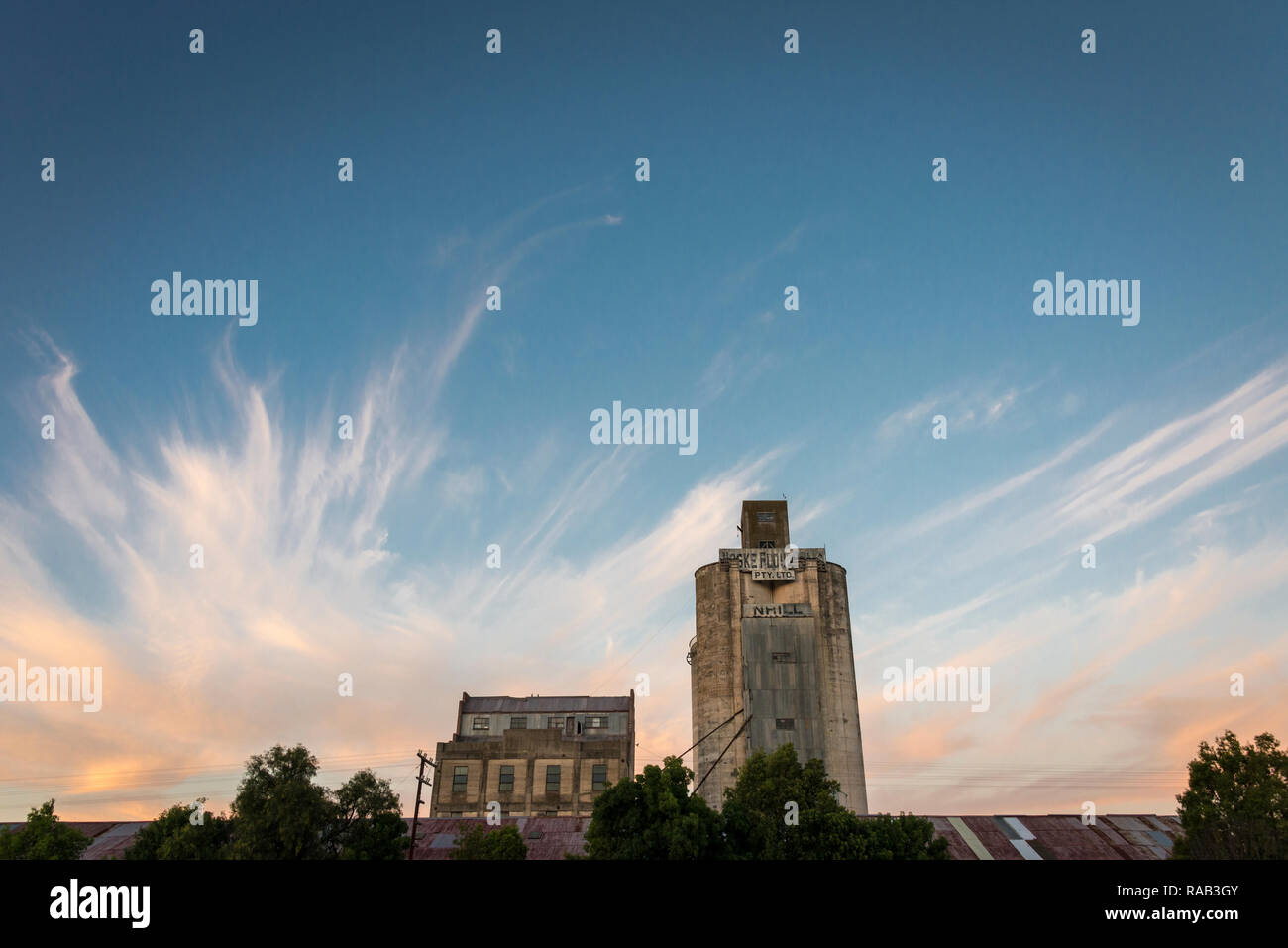 An old grain silo and buildings against a dramatic sunset sky in Nhill, Victoria Australia Stock Photo