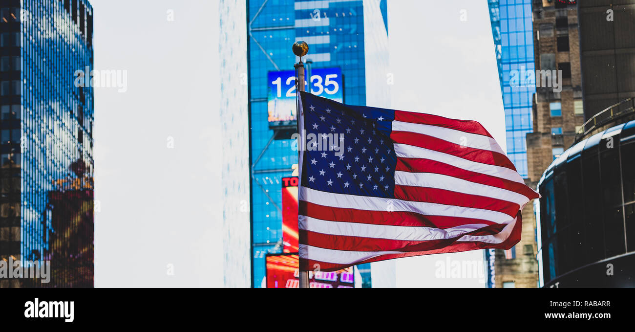 Close-up view of an American flag waving in Times Square in Manhattan. Blurred skyscrapers in the background. New York City, USA. Stock Photo