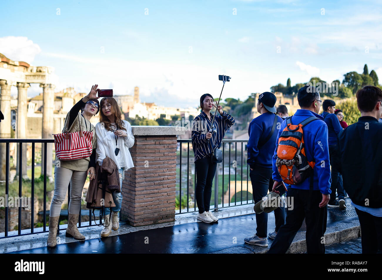 Some Chinese tourists are taking selfies in front of the beautiful Roman Forums in Rome, Italy. Stock Photo