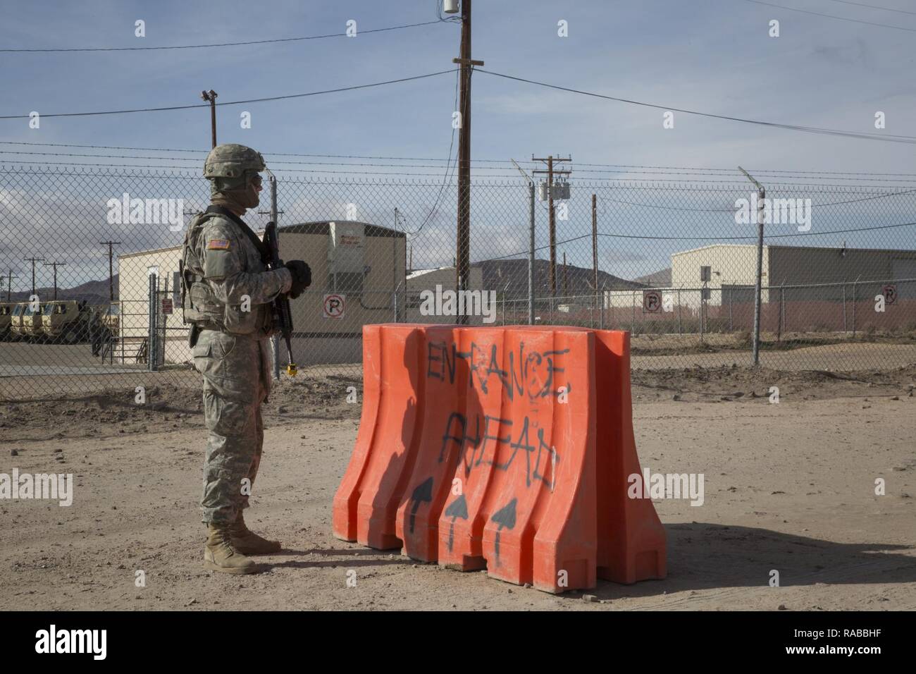 U.S. Army Spc. Triston Plumley, Military Police, 42nd Military Police Brigade, stands guard at the entrance to the rotational unit bivouac area of the National Training Center, Ft. Irwin, CA., Jan. 10, 2017. The National Training Center conducts tough, realistic, Unified Land Operations with our United Action Partners to prepare Brigade Combat Teams and other units for combat while taking care of Soldiers, Civilians, and Family members. Stock Photo