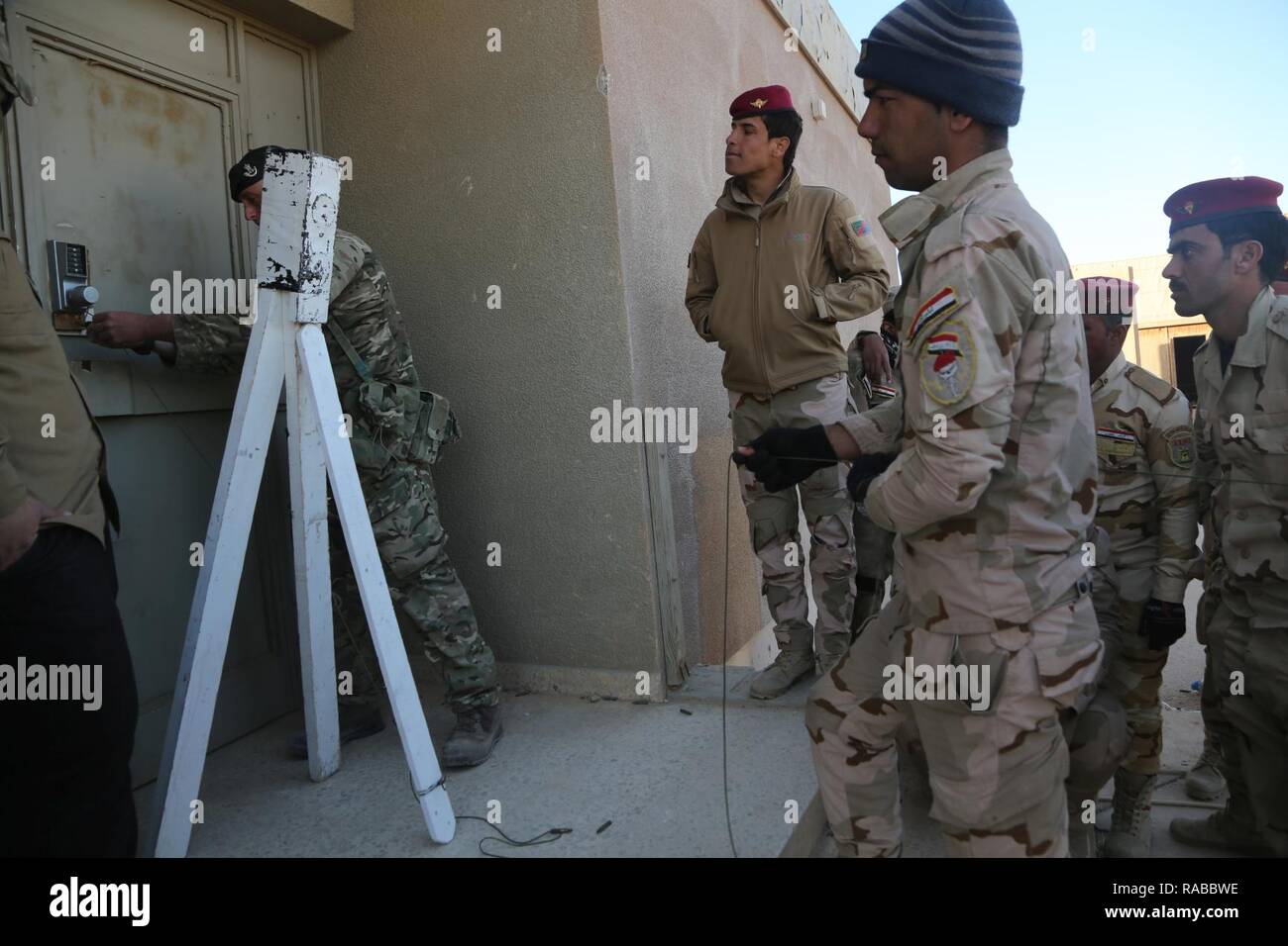 A British trainer assigned to 4th Battalion “The Rifles”  shows Iraqi security forces a method to safely open a door during counter-improvised explosive training at Al Asad Air Base, Iraq, Jan. 12, 2017. This training is part of the overall Combined Joint Task Force – Operation Inherent Resolve building partner capacity mission to train partnered forces fighting ISIL. CJTF-OIR is the global Coalition to defeat ISIL in Iraq and Syria. Stock Photo