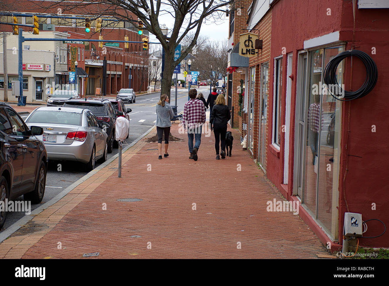 female walking her black dog to a male and female friend downtown
