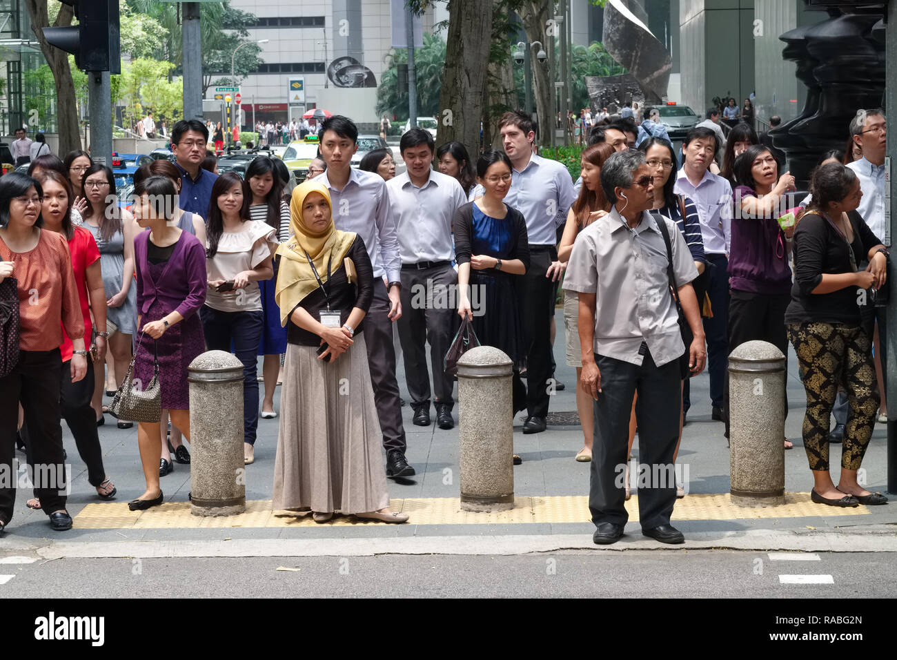 A crowd of ethnically mixed white-collar workers in Raffles Place banking and office district, during lunch break at a pedestrian crossing; Singapore Stock Photo