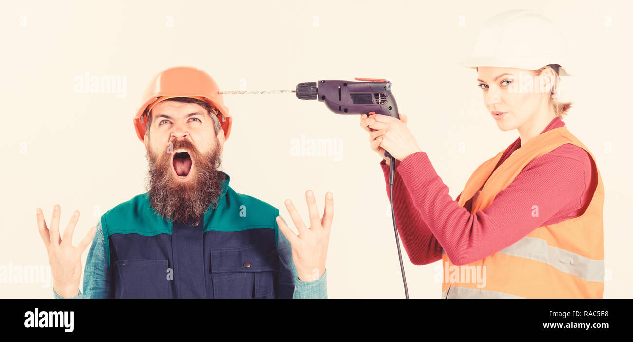 Husband annoyed by wife. Builder makes hole in male head. Marriage issues concept. Woman drills head of man, white background. Man in helmet with shouting face fed up of his wife drilling him. Stock Photo