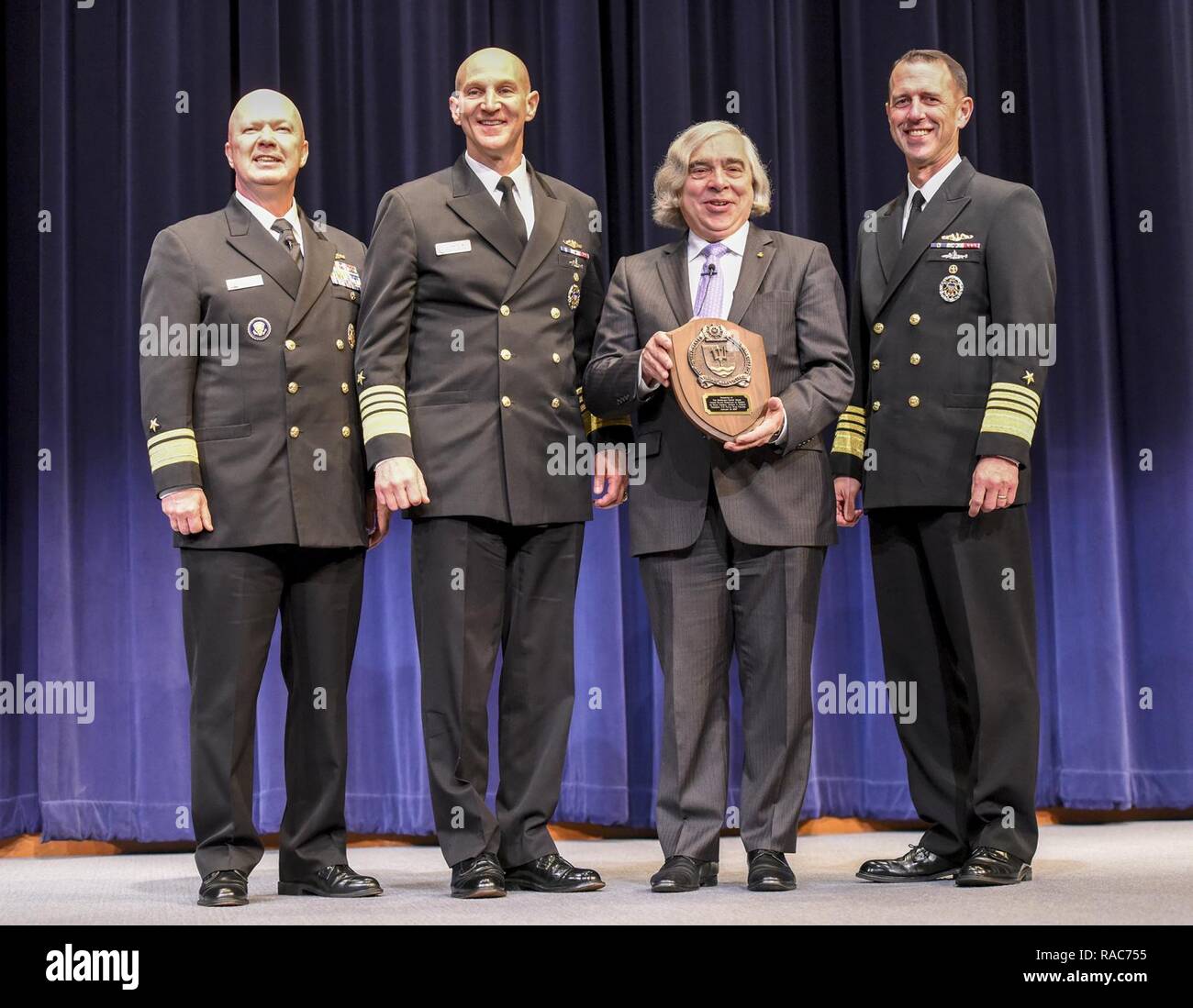 NEWPORT, R.I.  (Jan. 12, 2017)  Rear Adm. Jeffrey A. Harley, president, U.S. Naval War College (NWC), is joined onstage by Adm. James F. Caldwell Jr., director, naval nuclear propulsion program, Ernest Moniz, U.S. secretary of energy, and Adm. John M. Richardson, chief of naval operations, to present a commemorative plaque to Moniz as recognition for his visit to NWC. During his talk on nuclear security and strategy, Moniz highlighted the importance of science-based stockpile stewardship and the challenges ahead for nonproliferation and nuclear weapons policy. Stock Photo