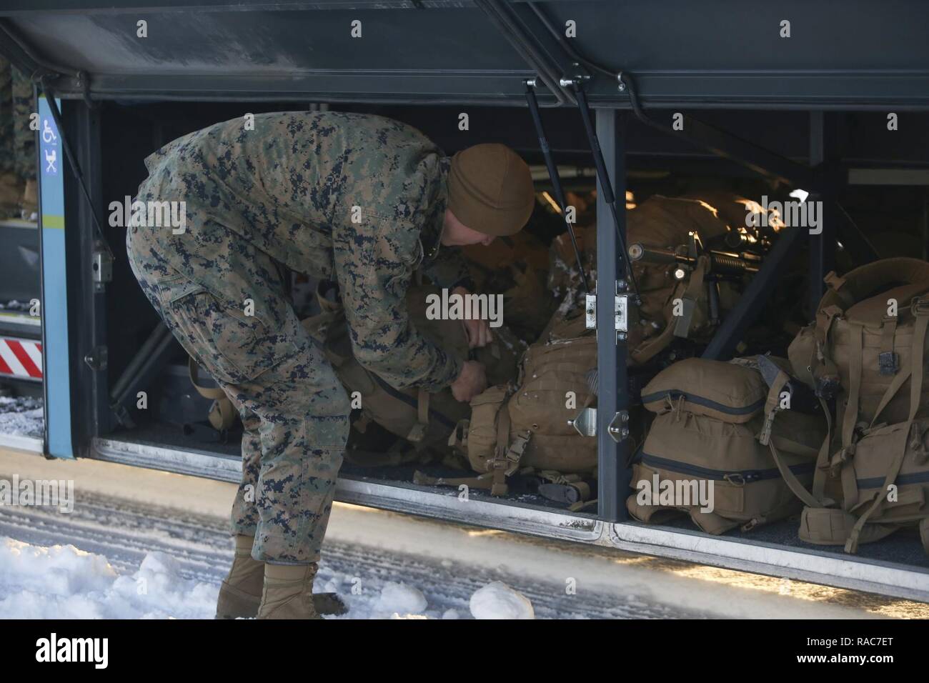 A U.S. Marine places his pack under the bus shortly after their plane landed at Vaernes Garnison, Norway, Jan. 16, 2017. The Marines with Black Sea Rotational Force arrived at Vaernes Garnison early in the morning as part of Marine Rotational Force Europe 17.1. Stock Photo