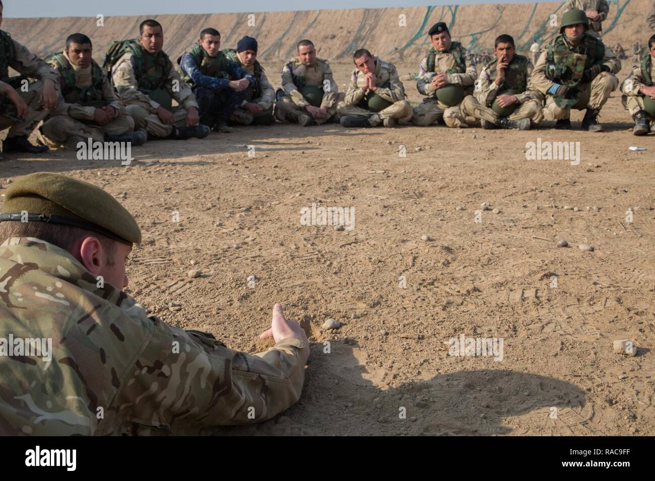A British soldier demonstrates how to properly expose a simulated improvised explosive device to Iraqi security forces soldiers at Camp Taji, Iraq, Jan. 19, 2017. This training is critical to enabling ISF to counter ISIL as they continue to liberate their homeland. Coalition forces conducted the training in support of Combined Joint Task Force – Operation Inherent Resolve, the global Coalition to defeat ISIL in Iraq and Syria. Stock Photo