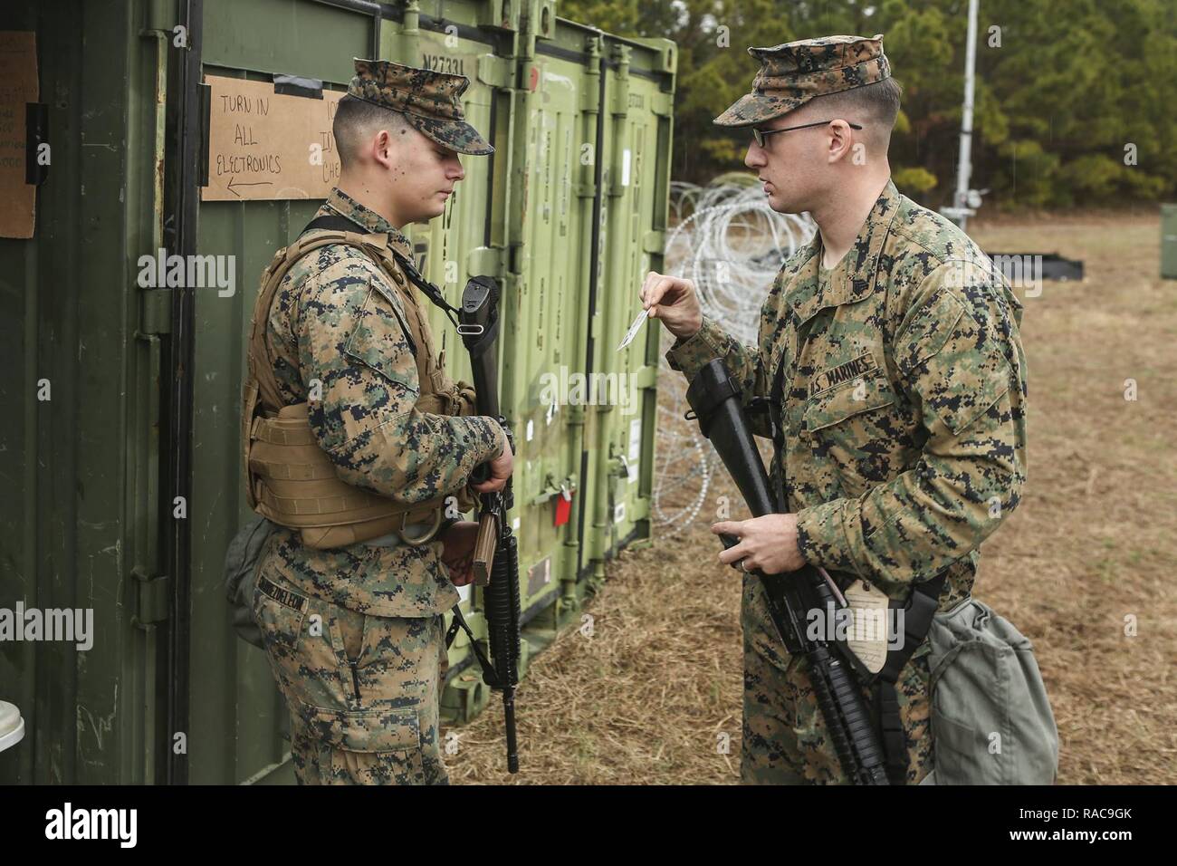U. S. Marine Corps Lance Cpl. Yosef A. Charriez-Deleleon, left, Embarkation Specialist, Service Company, Combat Logistics Regiment (CLR) 2, 2nd Marine Logistics Group, inspects a Marines Common Access Card while standing duty during a command post exercise (CPX) at Landing Zone Canary on Camp Lejeune, N.C., Jan. 18, 2016. CLR-2 conducted the CPX in preparation for an upcoming deployment. Stock Photo
