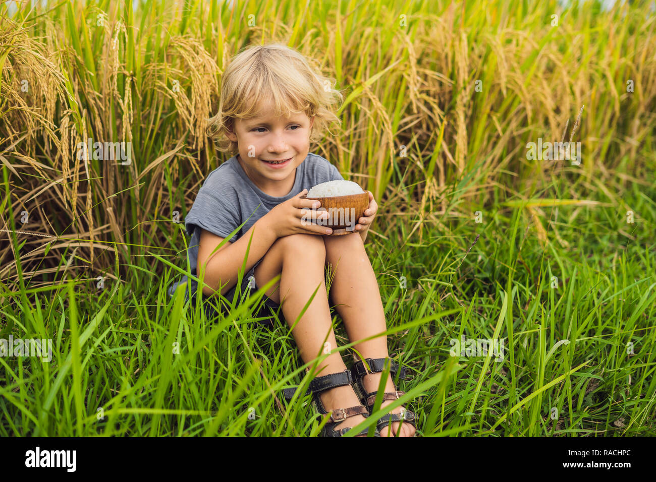Boy is holding a cup of boiled rice in a wooden cup on the background ...