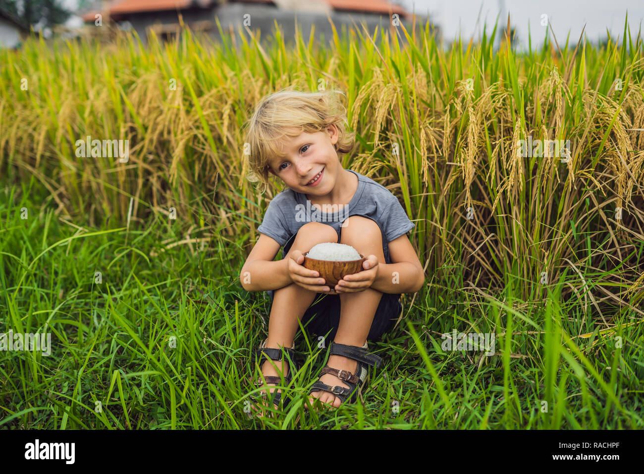 Boy is holding a cup of boiled rice in a wooden cup on the background ...