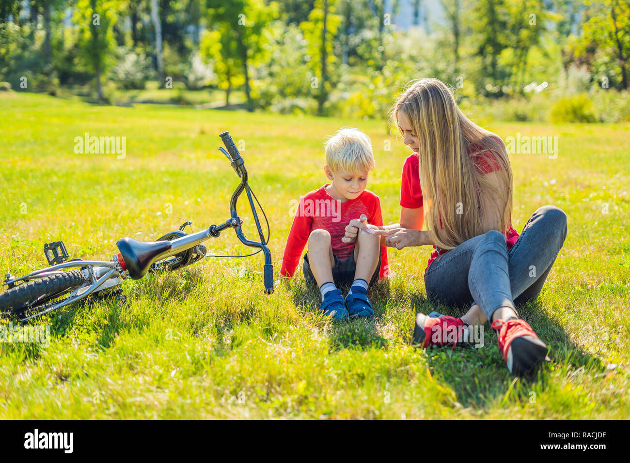 The boy fell off the bicycle, his mother pastes a plaster on his knee BANNER, LONG FORMAT Stock Photo