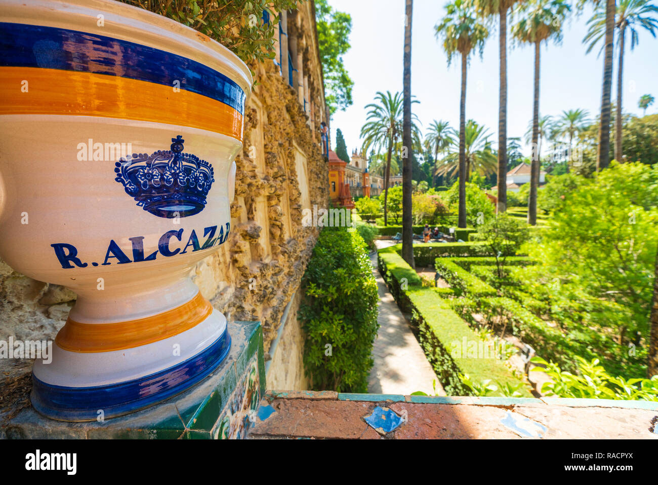 Decorated ceramic pot with royal symbol of crown on balustrade facing the lush gardens, Real Alcazar, UNESCO, Seville, Andalusia, Spain Stock Photo