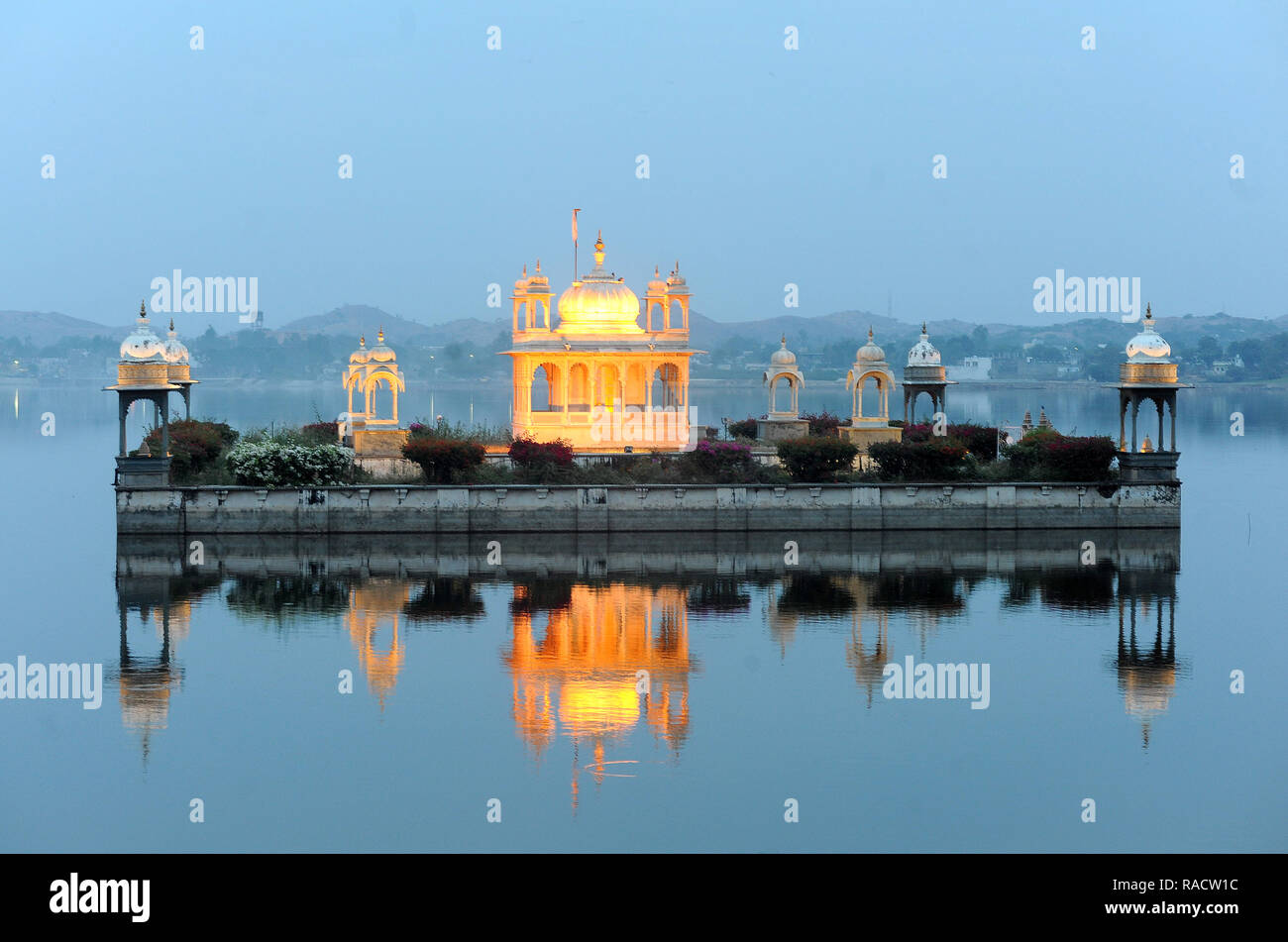 Vijay Raj Rajeshwar temple, reflected in the Gaibsagar Lake, built in 1923, lighting up at dusk for evening prayers, Dungarpur, Rajasthan, India, Asia Stock Photo