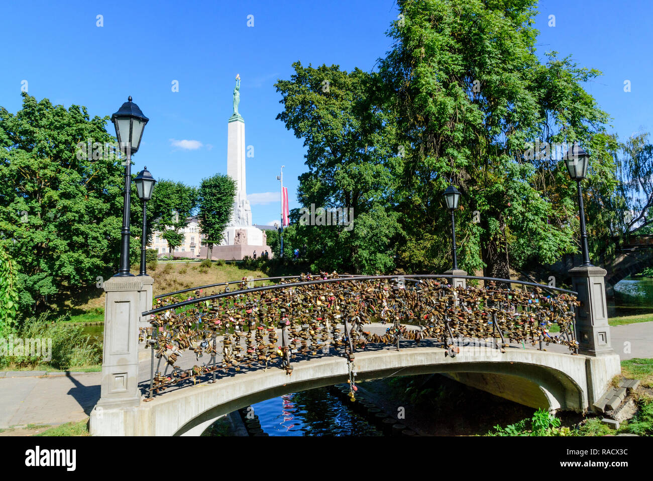 Freedom Monument and bridge with love lockets, Bastejkalna Parks, Riga, Latvia, Europe Stock Photo