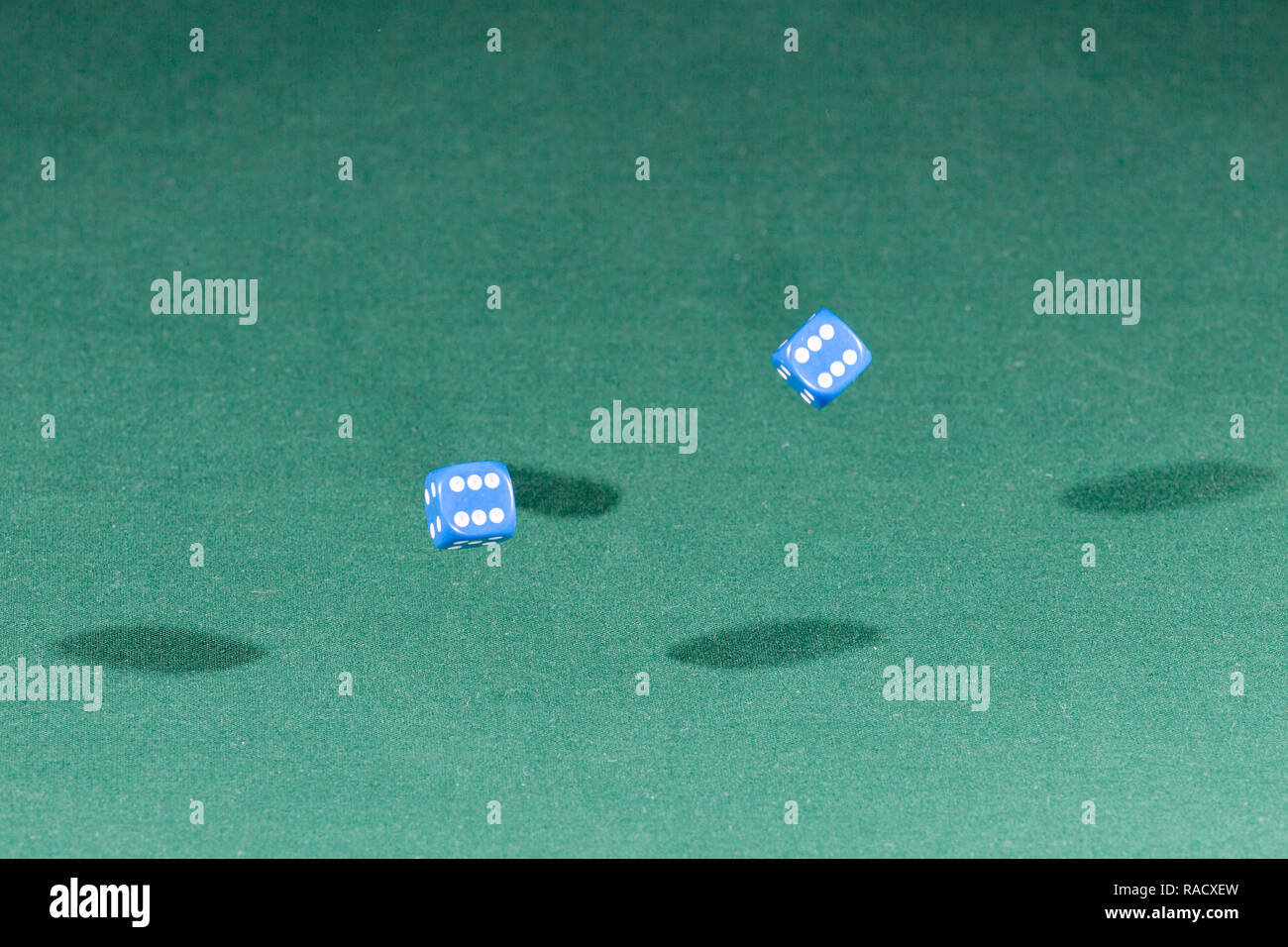 Two blue dices falling on a green table Stock Photo