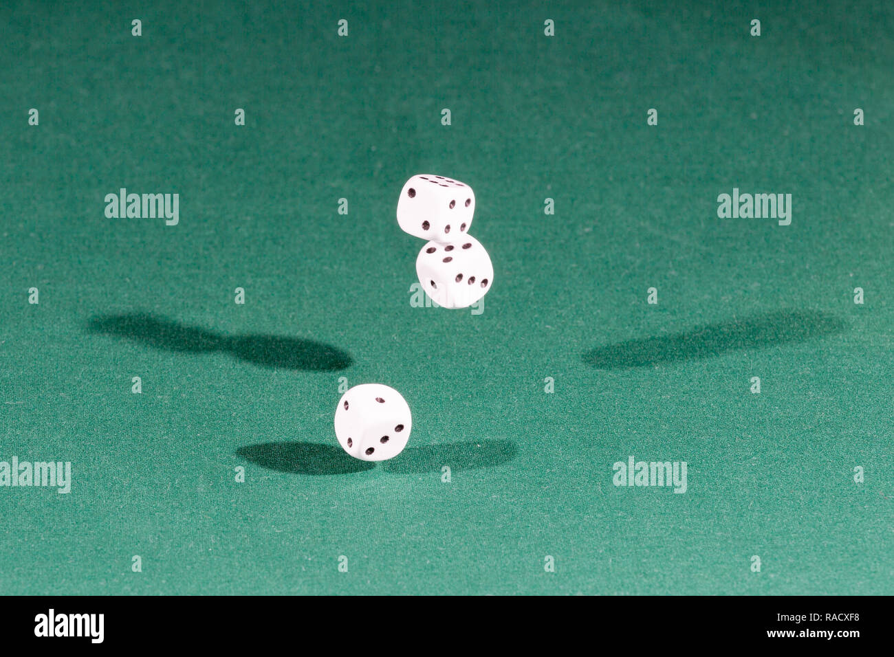 Three white dices falling on a green table Stock Photo
