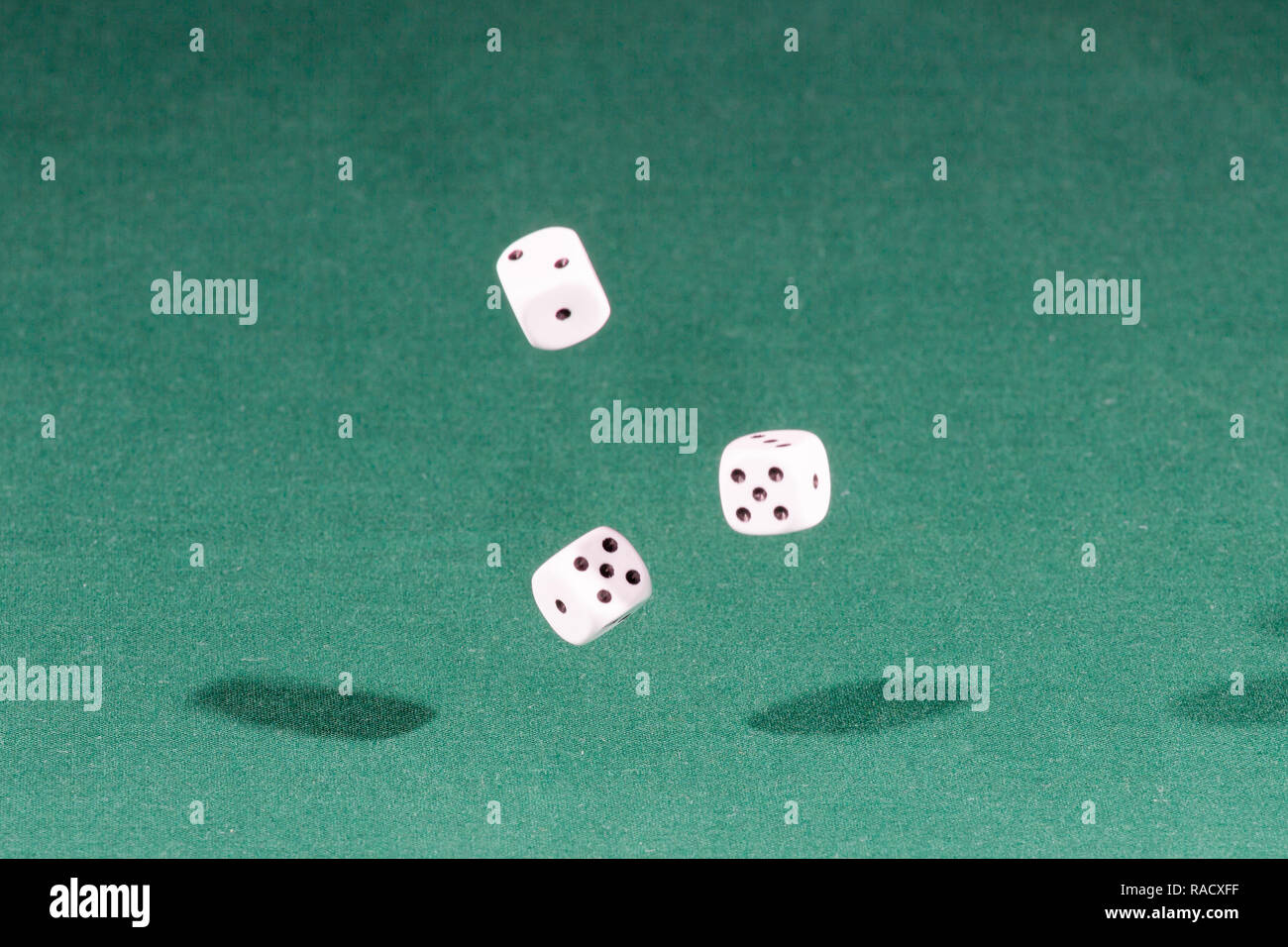 Three white dices falling on a green table Stock Photo