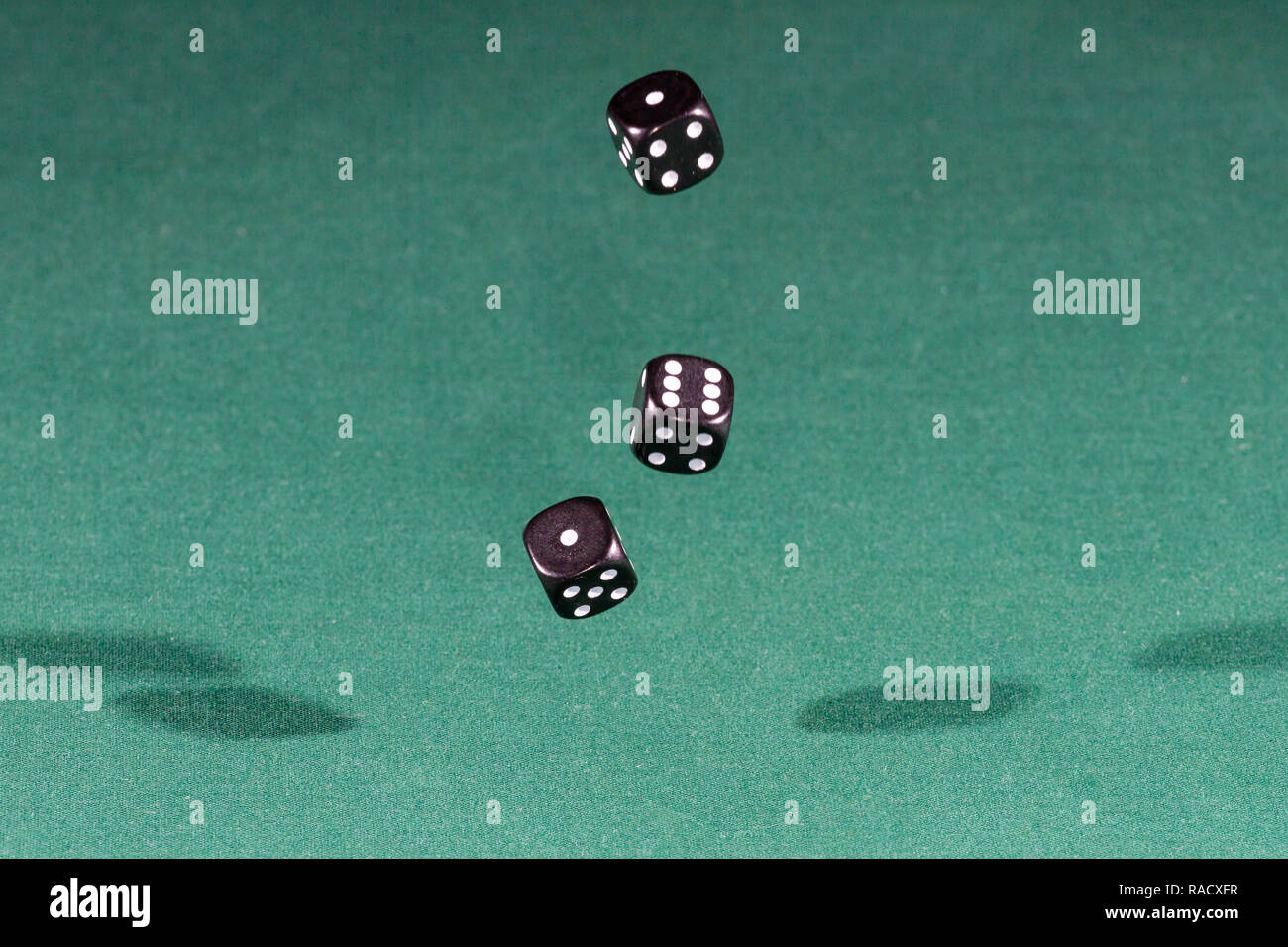 Three black dices falling on a green table Stock Photo