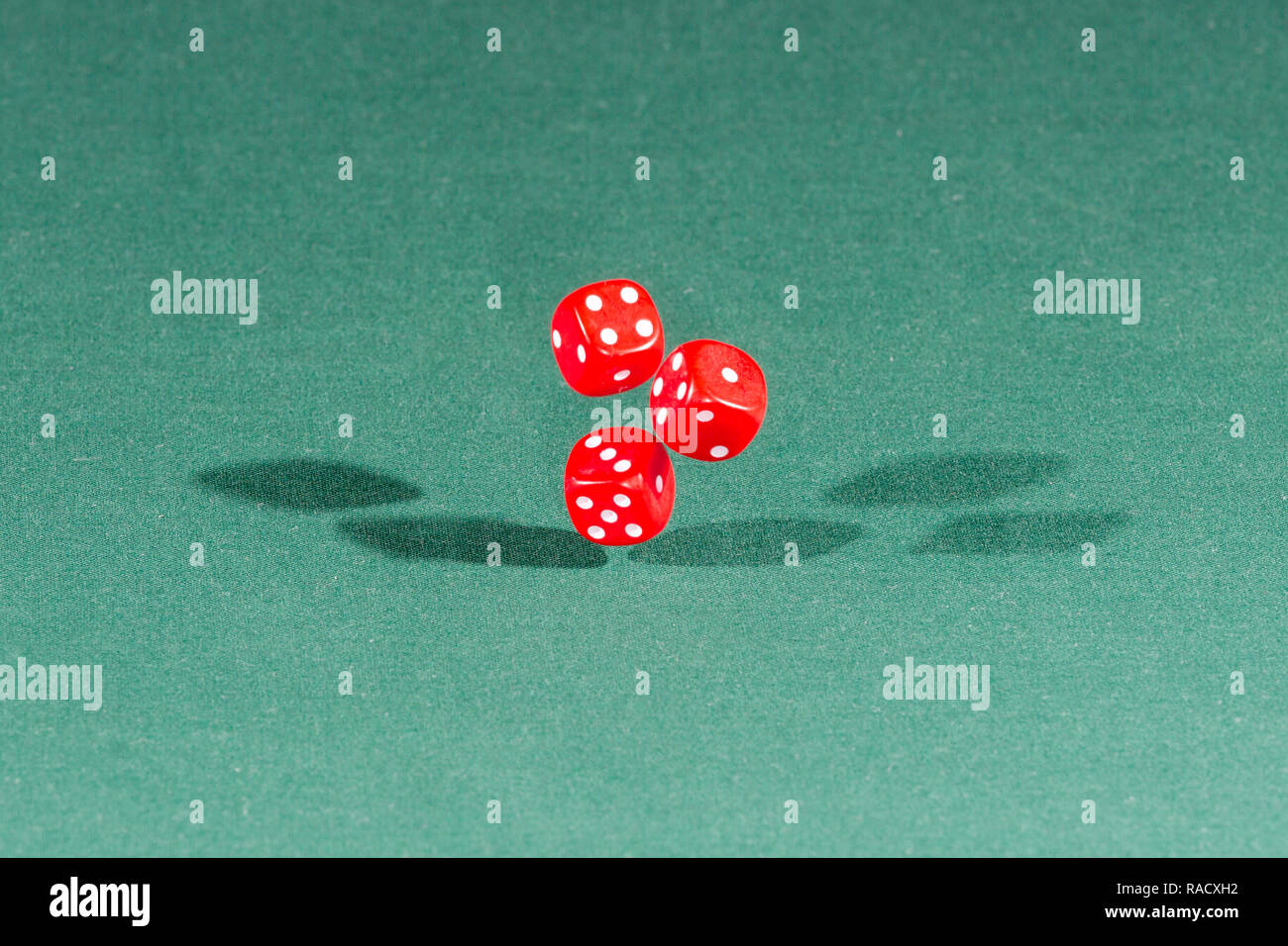 Three red dices falling on a green table Stock Photo