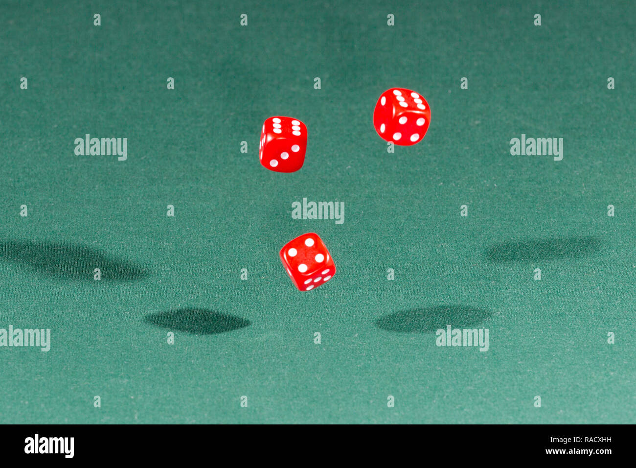 Three red dices falling on a green table Stock Photo
