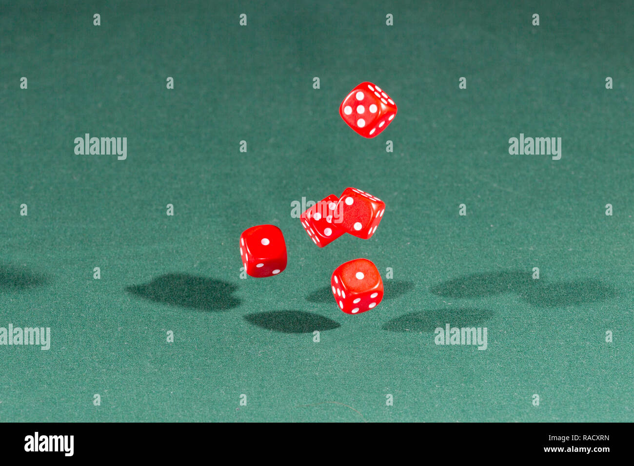 Five red dices falling on a green table Stock Photo
