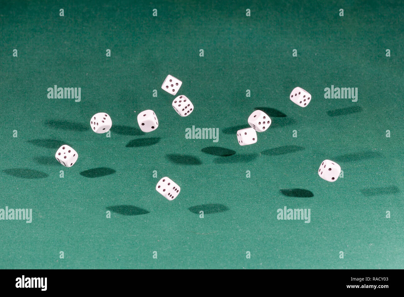 Ten white dices falling on a green table Stock Photo