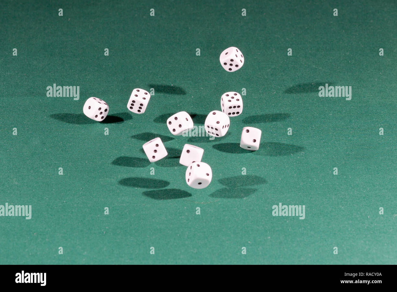 Ten white dices falling on a green table Stock Photo