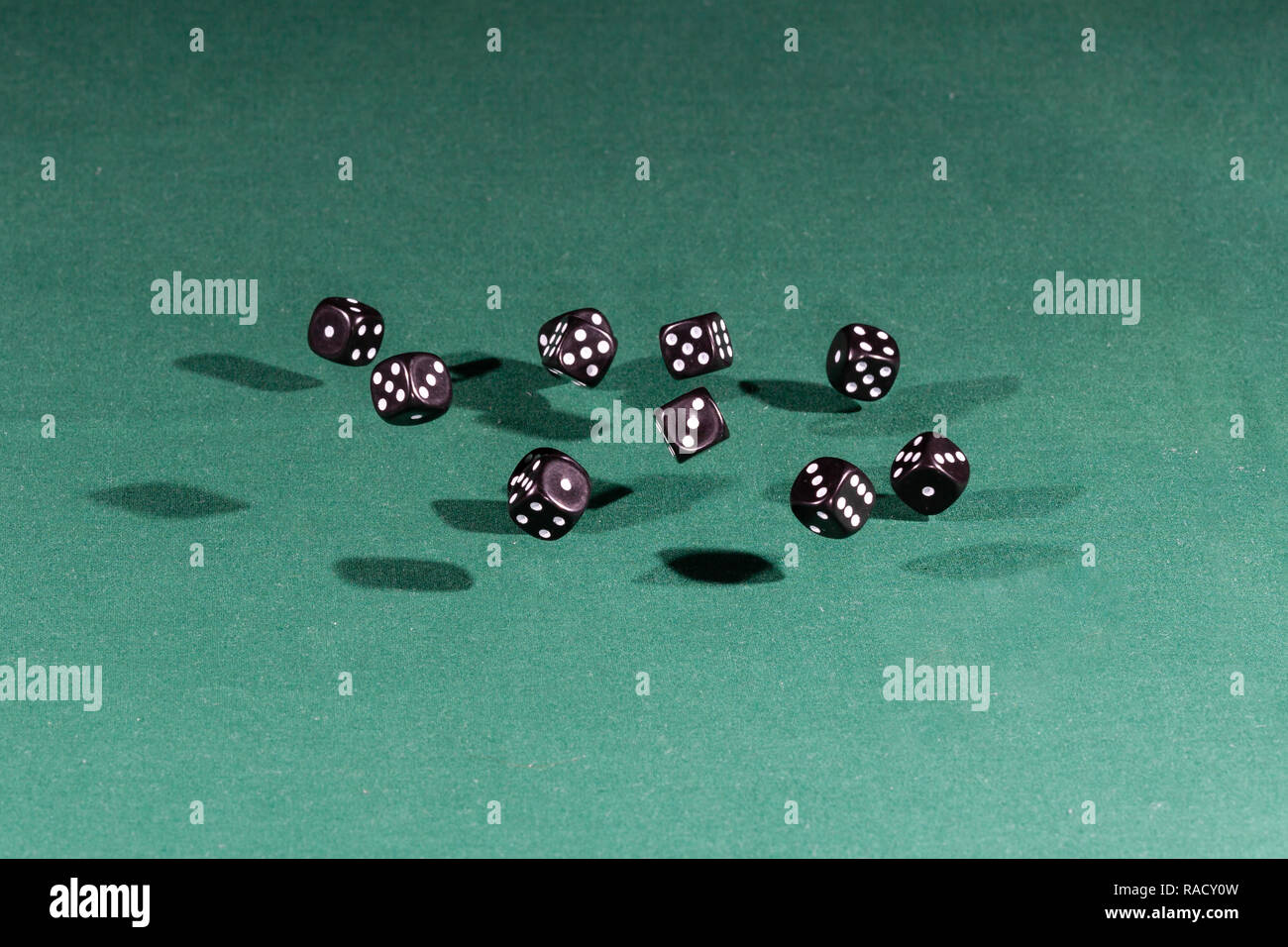 Ten black dices falling on a green table Stock Photo