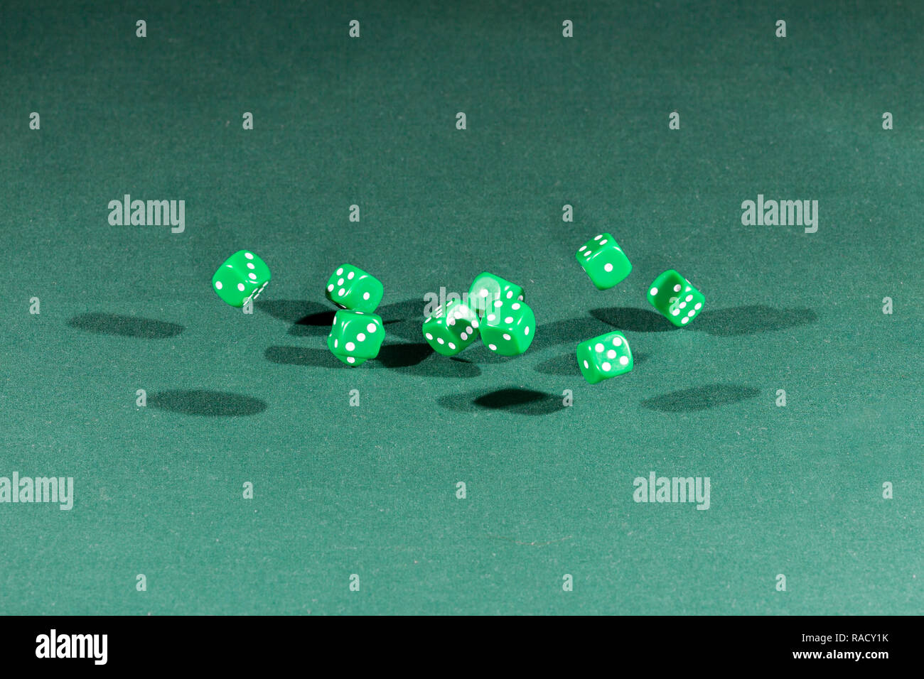 Ten green dices falling on a green table Stock Photo