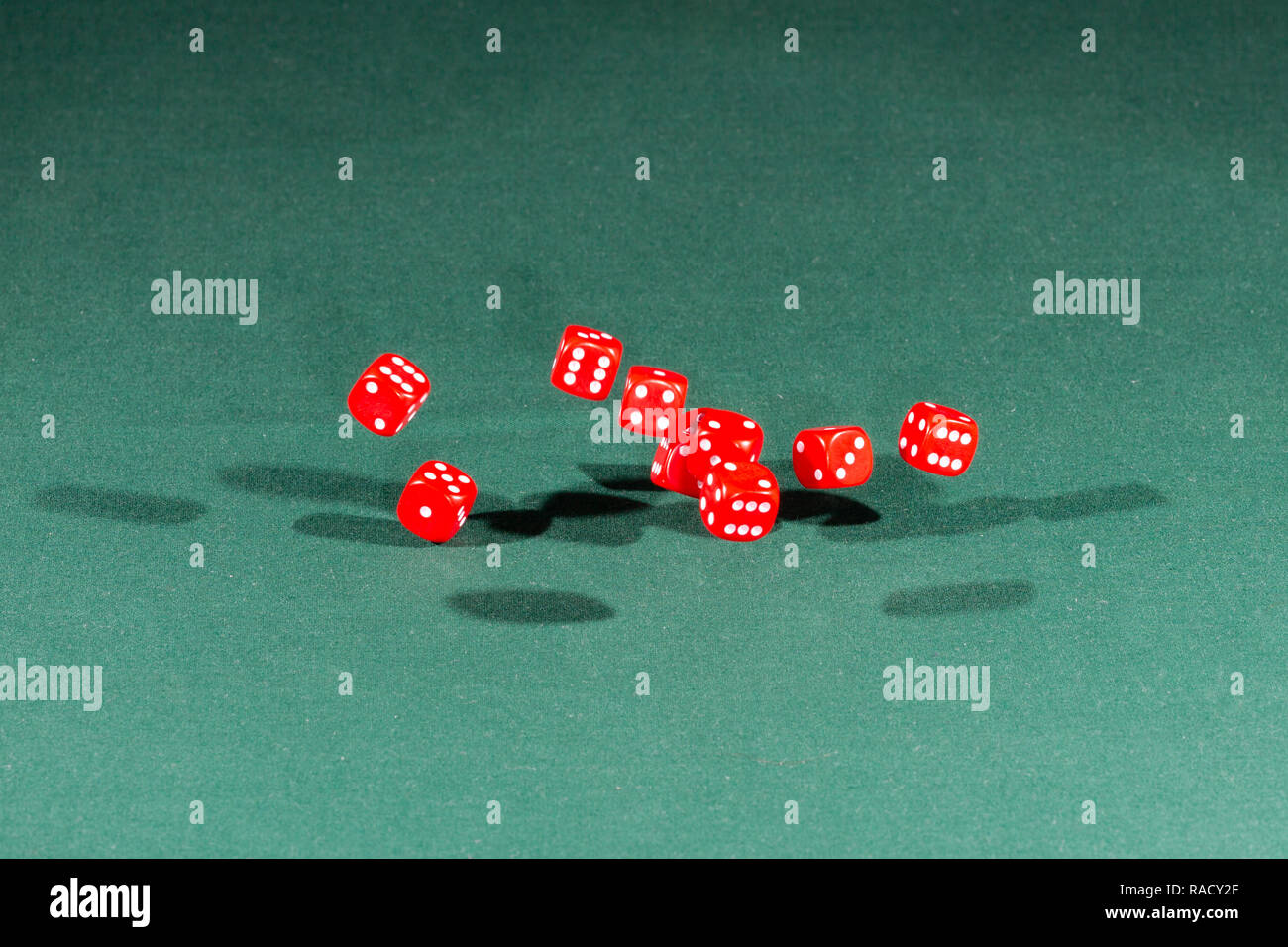 Ten red dices falling on a green table Stock Photo