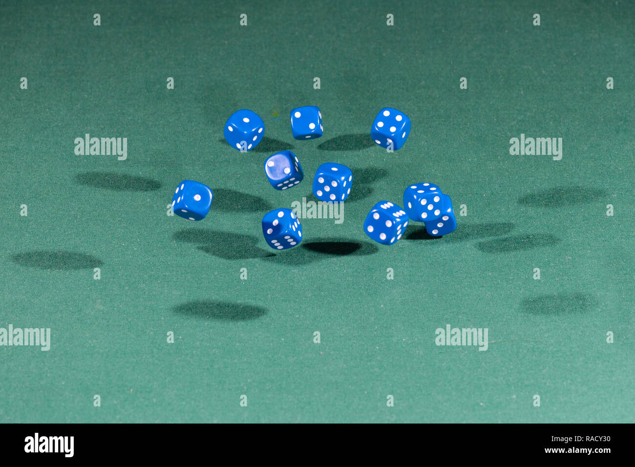 Ten blue dices falling on a green table Stock Photo