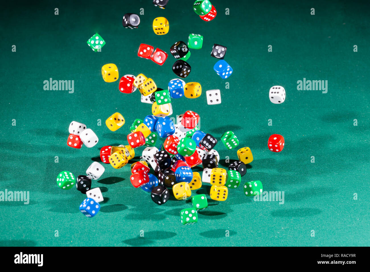 Hundred colored dices falling on a green table Stock Photo