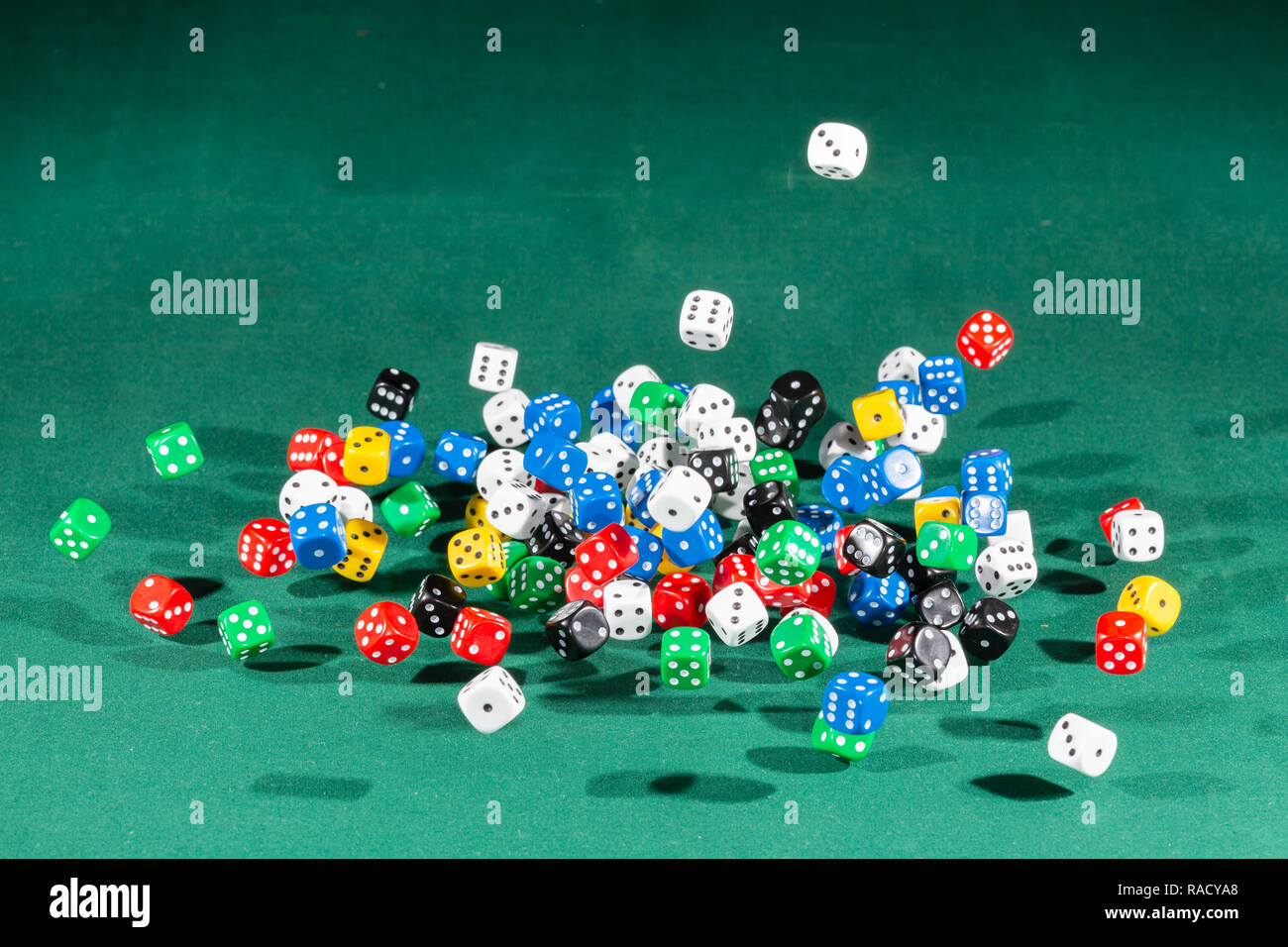 Hundred colored dices falling on a green table Stock Photo