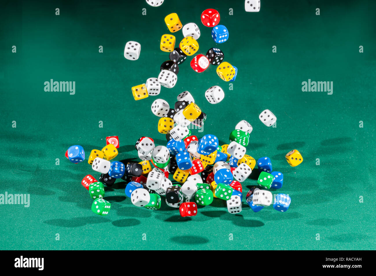 Hundred colored dices falling on a green table Stock Photo
