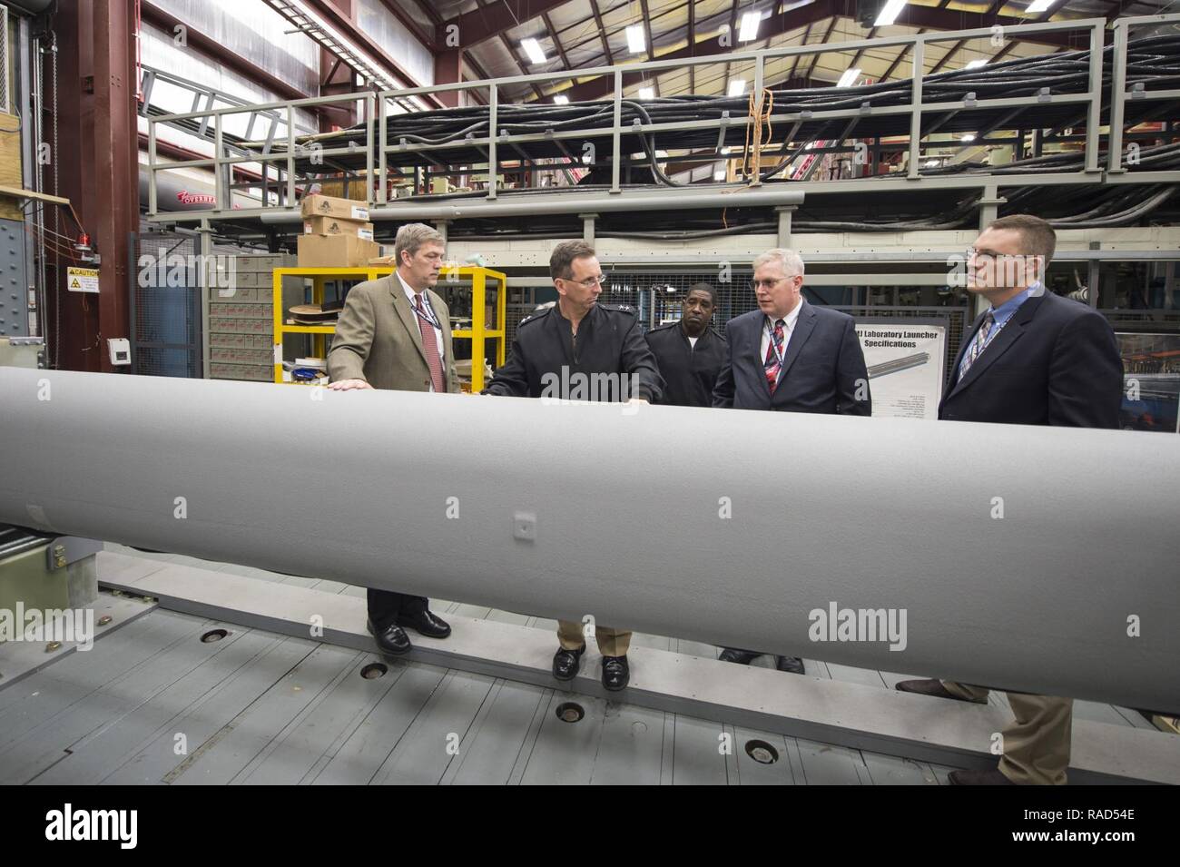 DAHLGREN (Jan. 12, 2017) Tom Boucher, second from right, program manager for the Electromagnetic Railgun at the Office of Naval Research (ONR), talks to Rear Adm. David Hahn, chief of naval research, during a visit to the railgun facility located at Naval Surface Warfare Center, Dahlgren Division. The EM Railgun launcher is a long-range weapon that fires projectiles using electricity instead of chemical propellants. Magnetic fields created by high electrical currents accelerate a sliding metal conductor, or armature, between two rails to launch projectiles at 4,500 mph. Stock Photo